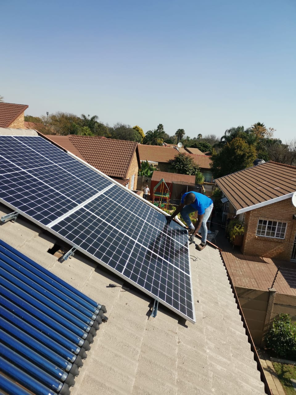worker installing solar panel on roof